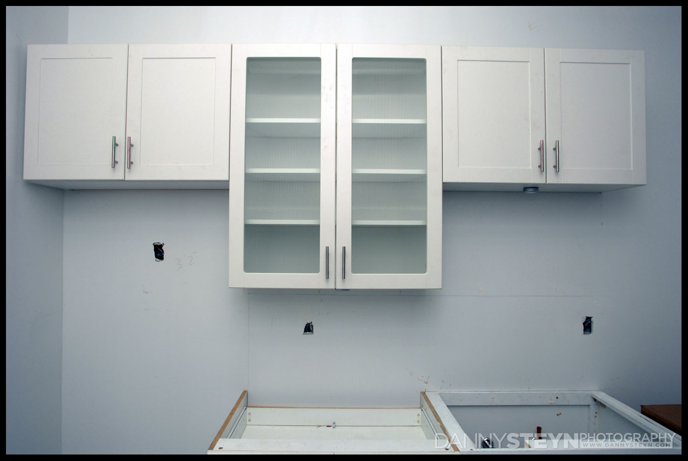 Kitchen cabinets being installed, room for the sink.