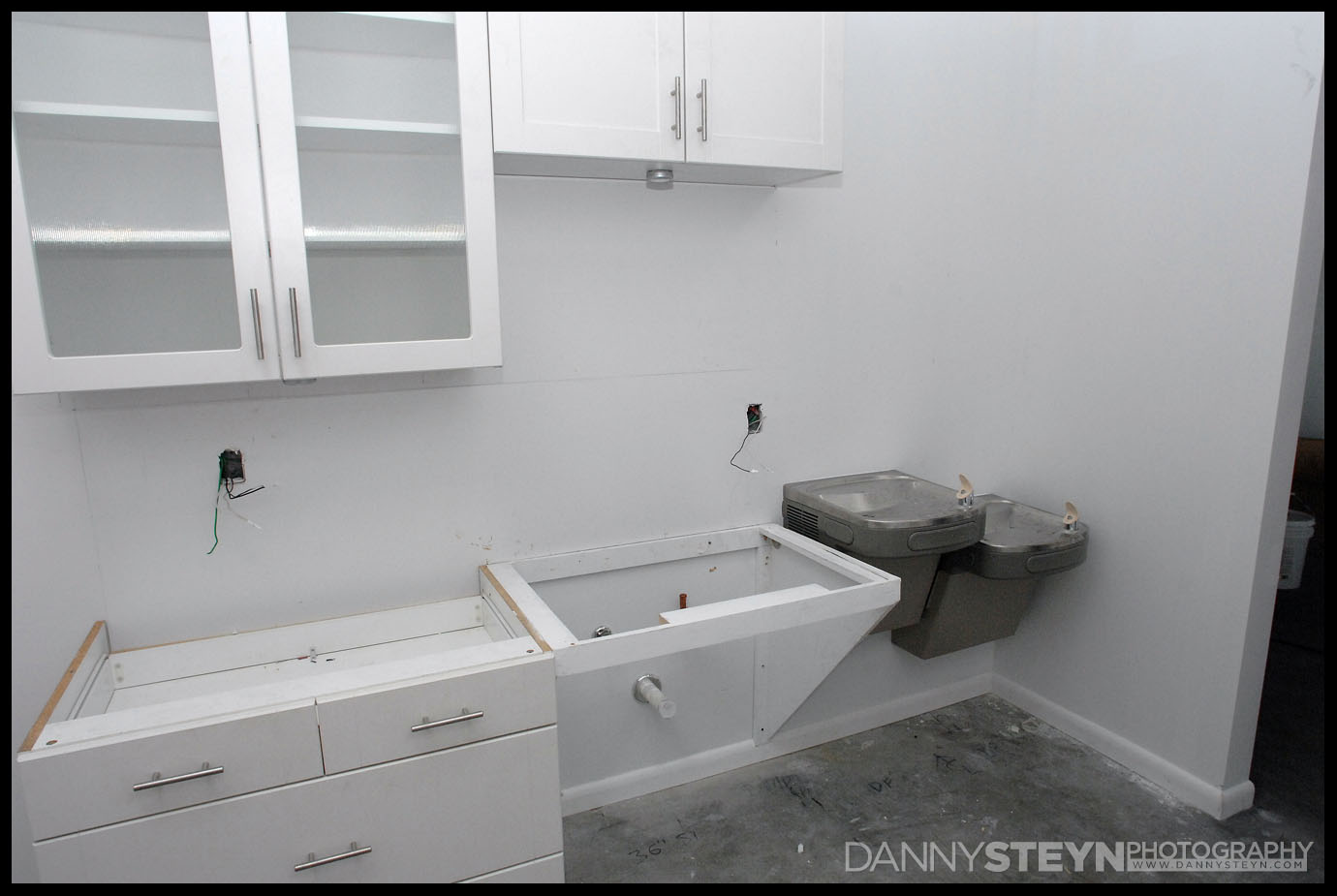 Kitchen cabinets being installed, room for the sink and the two ADA drinking fountains