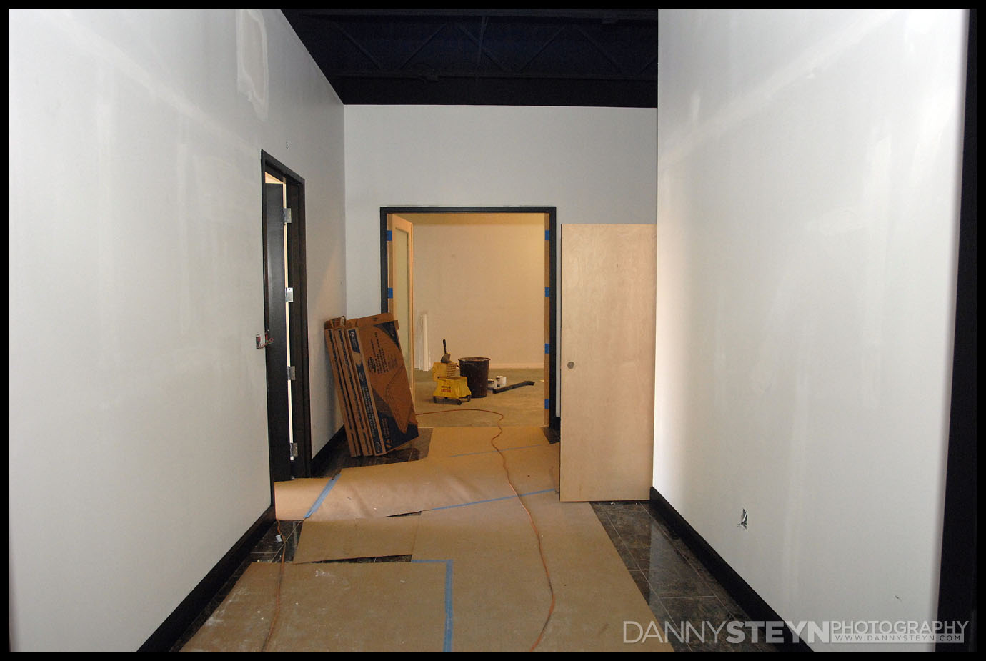 Photo Studio Gallery showing marble floor, black 8ft doors with frosted glass, and black baseboards.